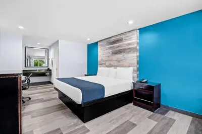 a bedroom with a bed and a blue wall at SureStay Hotel by Best Western Buena Park Anaheim in Buena Park