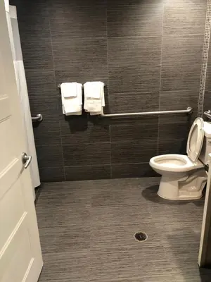a bathroom with a toilet and towels on a wall at American Inn Downey in Downey