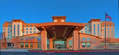 a building with a large building with a flag on it at Embassy Suites Palmdale in Palmdale