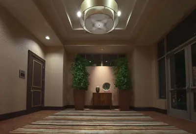 a hallway with two plants and a chandelier at Embassy Suites Palmdale in Palmdale