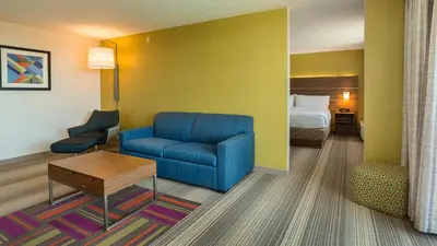 a hotel room with a blue couch and a bed at Holiday Inn Express Fullerton-Anaheim by IHG in Fullerton