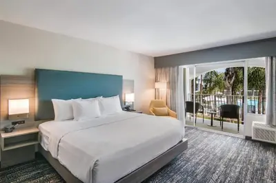 a hotel room with a large bed and a balcony at Hourglass Hotel, Trademark Collection by Wyndham in Bakersfield