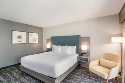 a bedroom with a large white bed and a chair at Hourglass Hotel, Trademark Collection by Wyndham in Bakersfield