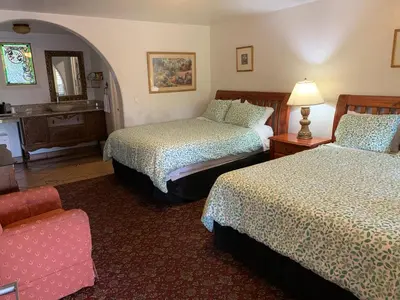 a hotel room with two beds and a chair at Chantico Inn in Ojai