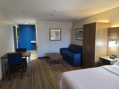 a hotel room with a bed and a blue couch at Holiday Inn Express & Suites Woodland Hills by IHG in Woodland Hills