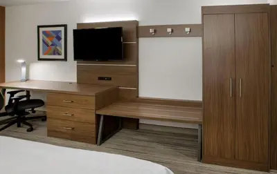 a hotel room with a desk with a tv and a bed at Holiday Inn Express & Suites Woodland Hills by IHG in Woodland Hills