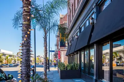 a city street with palm trees and a building at H by H Hospitality in Los Angeles