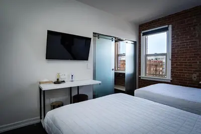 a hotel room with two beds and a television at H by H Hospitality in Los Angeles