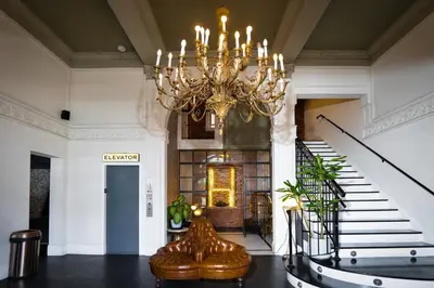 a chandelier is hanging in a hallway with stairs at H by H Hospitality in Los Angeles