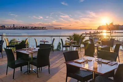 a restaurant with tables and chairs with a view of the water at Hotel Maya in Long Beach