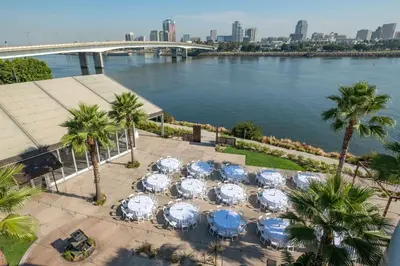 a bunch of tables with umbrellas next to a river at Hotel Maya in Long Beach