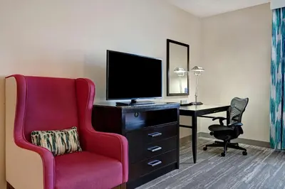 a room with a chair and a desk with a television at Hilton Garden Inn San Bernardino in San Bernardino