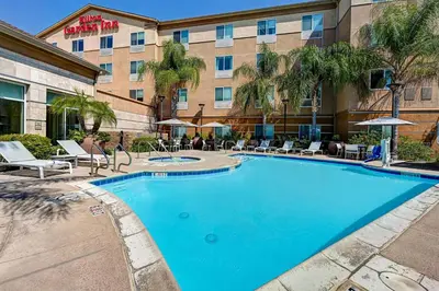 a hotel with a large swimming pool in front of a building at Hilton Garden Inn San Bernardino in San Bernardino