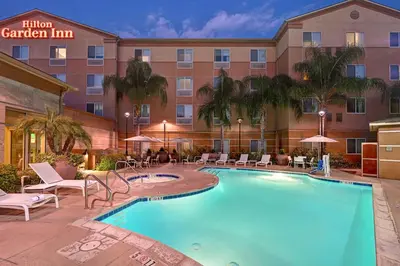 a hotel with a large swimming pool in front of a building at Hilton Garden Inn San Bernardino in San Bernardino