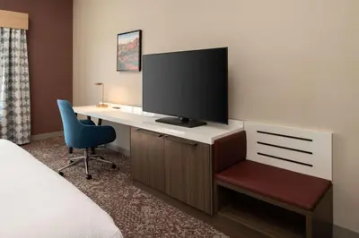 a hotel room with a desk with a tv and a chair at Hilton Garden Inn Fontana in Fontana