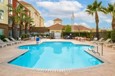 a pool at a hotel with chairs and palm trees at Hilton Garden Inn Fontana in Fontana