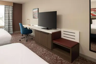 a hotel room with a desk with a tv and a chair at Hilton Garden Inn Fontana in Fontana