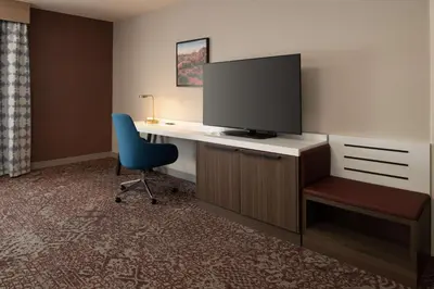 a room with a desk with a tv and a chair at Hilton Garden Inn Fontana in Fontana