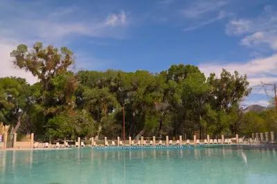 a swimming pool with chairs and trees in the background at Soledad Canyon Cottage 5 in Ravenna
