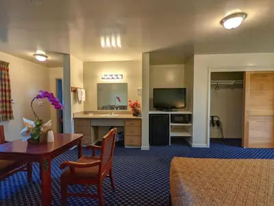 a hotel room with a dining table and a living room at Americas Best Value Inn Oxnard-Port Hueneme in Port Hueneme
