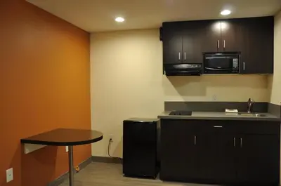 a kitchen with black cabinets and a small table at Motel 6 Maple/Main in Hesperia