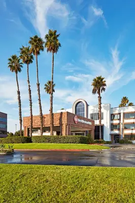 a building with palm trees in front of a street at Best Western Plus Meridian Inn & Suites, Anaheim-Orange in Orange