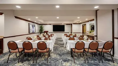 a conference room with tables and chairs and a screen at Ayres Hotel Redlands - Loma Linda in Redlands