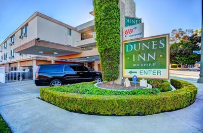 a sign in front of a building with a car at Dunes Inn - Wilshire in Los Angeles