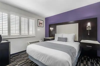 a hotel room with a large bed and purple walls at SureStay Hotel by Best Western Beverly Hills West LA in Los Angeles