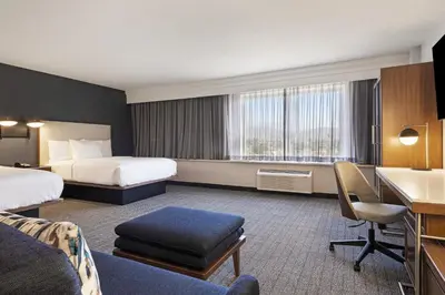 a hotel room with two beds and a desk at Courtyard by Marriott Baldwin Park in Baldwin Park