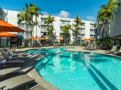 a swimming pool with chairs and umbrellas in a hotel at Ventura Beach Marriott in Ventura