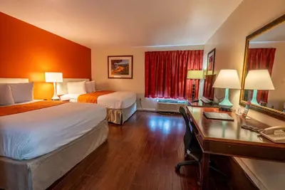 a hotel room with two beds and a desk at Howard Johnson by Wyndham Buena Park in Buena Park