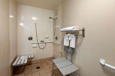 a bathroom with a shower and a bench in it at Quality Inn Placentia Anaheim Fullerton in Placentia
