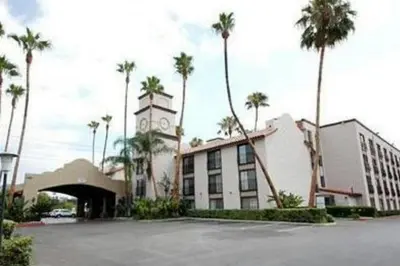 a building with a clock tower and palm trees at The Buena Park Grand Hotel & Suites in Buena Park