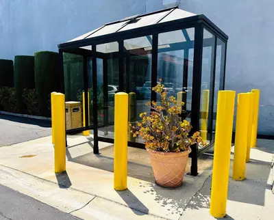 a bus stop with a potted plant and yellow poles at The Hills Inn Eagle Rock - Near Old Town Pasadena in Los Angeles
