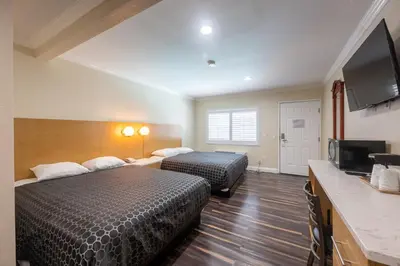 a hotel room with two beds and a flat screen tv at Hollywood City Inn in Los Angeles
