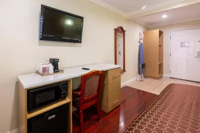 a room with a desk with a television on the wall at Hollywood City Inn in Los Angeles
