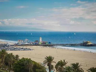 a beach with a pier and a group of people at Fairmont Miramar Hotel & Bungalows in Los Angeles
