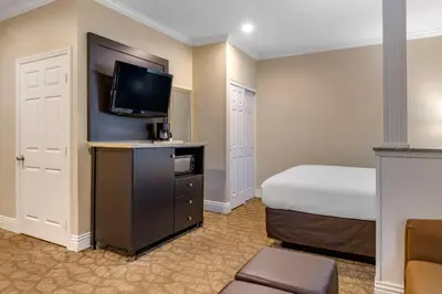 a hotel room with a bed and a flat screen tv at Comfort Inn & Suites Huntington Beach in Huntington Beach