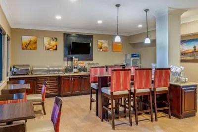 a dining room with a table and chairs and a television at Comfort Inn & Suites Huntington Beach in Huntington Beach
