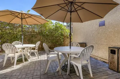 two tables and chairs with umbrellas on a patio at Comfort Inn & Suites Huntington Beach in Huntington Beach