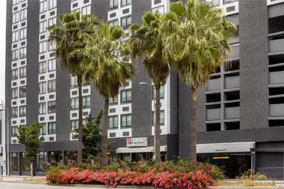 a building with palm trees and flowers in front of it at Hilton Garden Inn LAX Los Angeles Airport in Los Angeles
