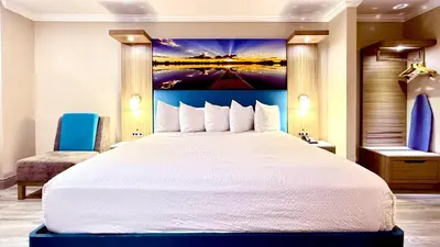 a bedroom with a large bed with a painting on the wall at Days Inn by Wyndham Los Angeles LAX South Bay Beach City LA in Lawndale