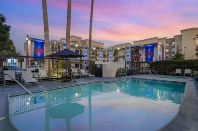 a swimming pool at a resort with tables and chairs at Best Western Courtesy Hotel - Anaheim Resort Amusement Park in Anaheim
