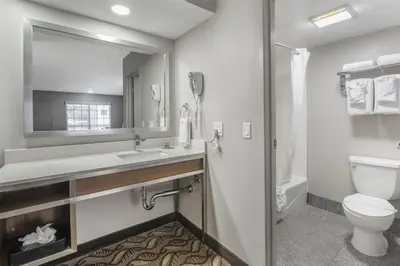a bathroom with a toilet and a sink and a mirror at Best Western Airport Plaza Hotel – LAX Airport LA Stadium in Los Angeles