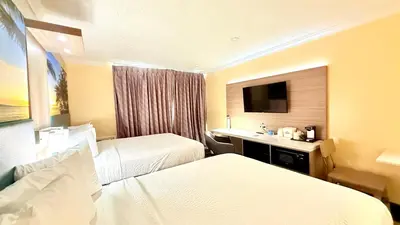 a hotel room with two beds and a television at Days Inn by Wyndham Los Angeles LAX Airport Stadium Area in Los Angeles