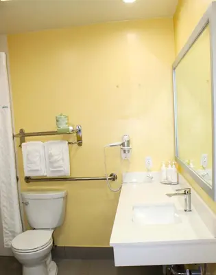 a bathroom with a toilet and a sink and a mirror at Days Inn by Wyndham Los Angeles LAX Airport Stadium Area in Los Angeles