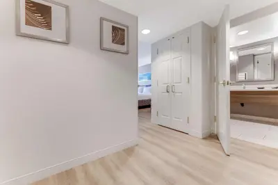 a hallway with white walls and a white door with a mirror at Sonesta Anaheim Resort Area in Anaheim