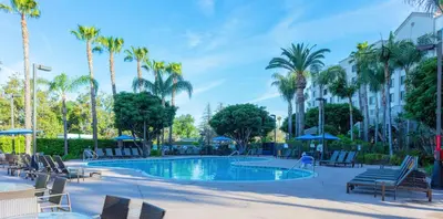 a pool with chairs and palm trees and a building at Sonesta ES Suites Anaheim Resort Area in Anaheim