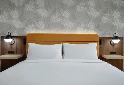 a bedroom with a bed with white pillows and a wallpaper at Sonesta Los Angeles Airport LAX in Los Angeles